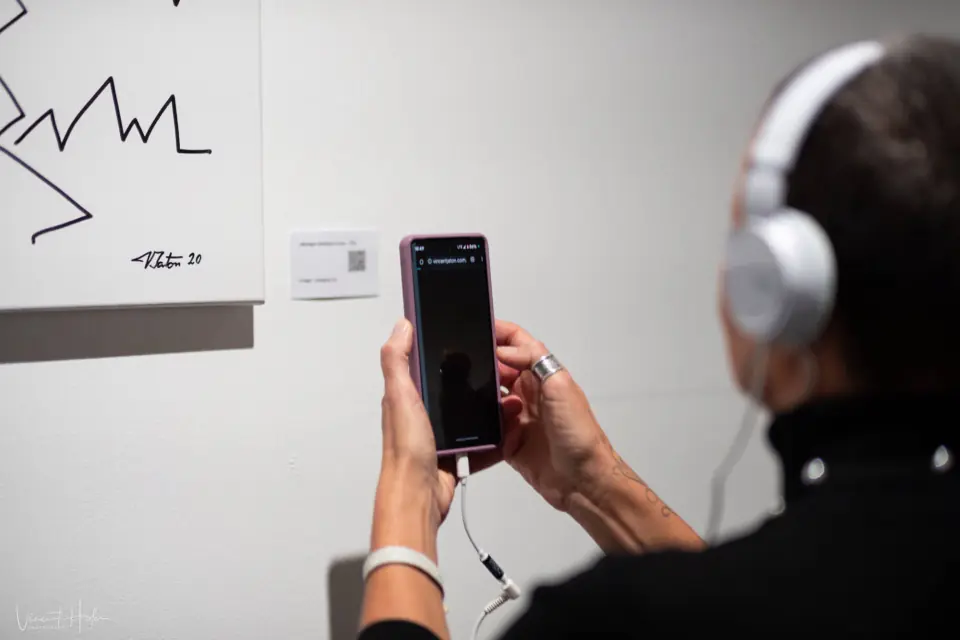 Visiteuse écoutant sur son smartphone la musique associée à une œuvre